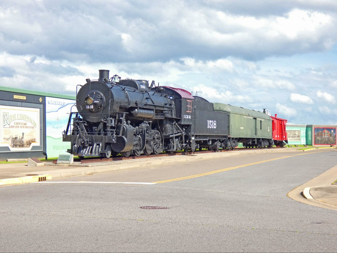 A wall of murals with train in front.