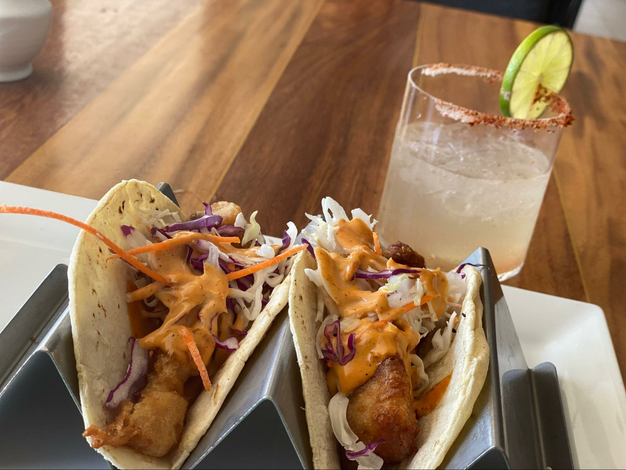 two crispy fish tacos served with a mezcalita cocktail