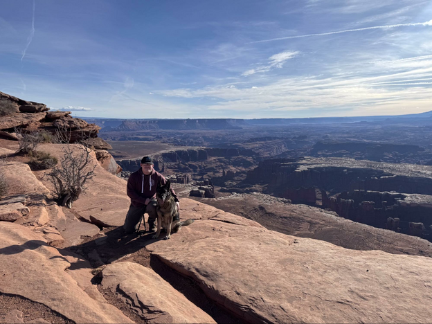 Man with a dog overlooking a canyon.