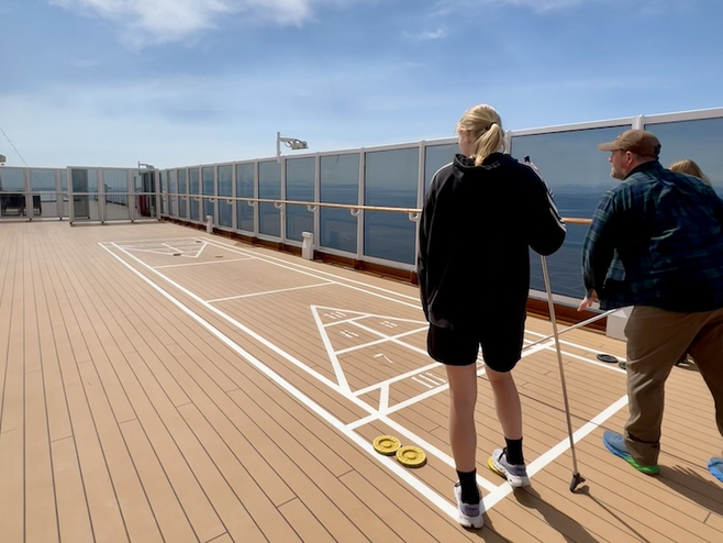 Couple playing shuffleboard on the deck