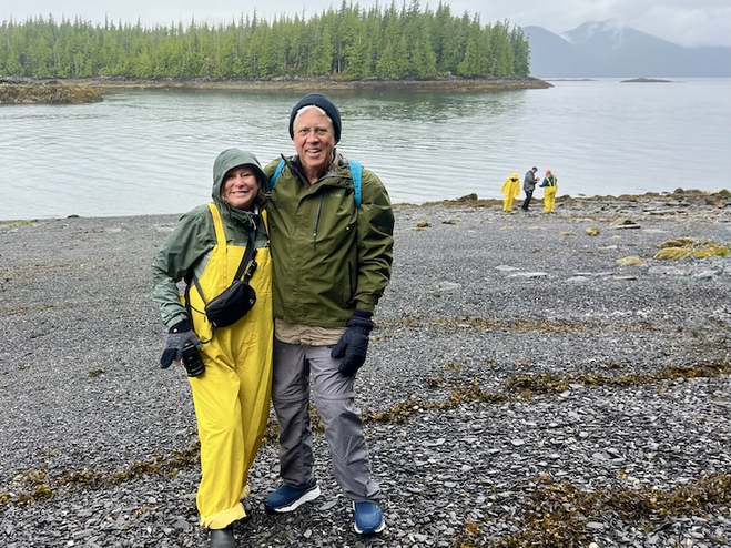 Couple on the shore of an island with trees and mountains
