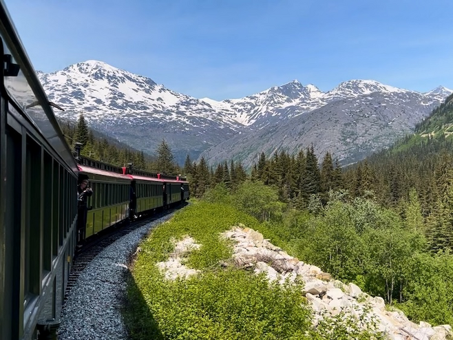 Train ascending the mountain pass surrounded by snow topped mountains