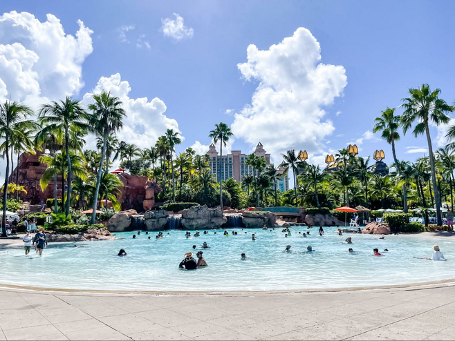 View of a pool filled with people at Atlantis, with palm trees and the resort towers in the background.