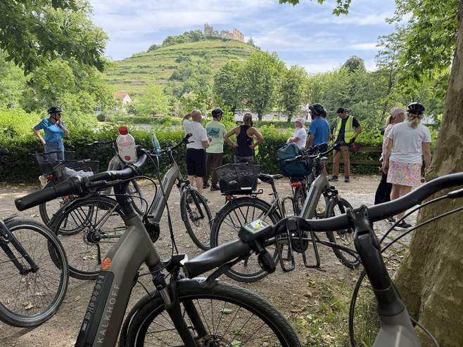 Bicycles parked with people in background and view of sunny hill with old castle ruins