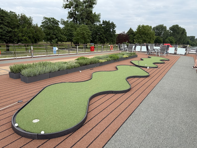 Green mini-golf putting greens next to a walking path and an herb garden