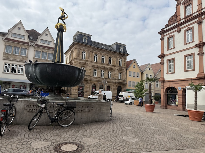 Bicycles parked next to an old fountain in a small European town with buildings