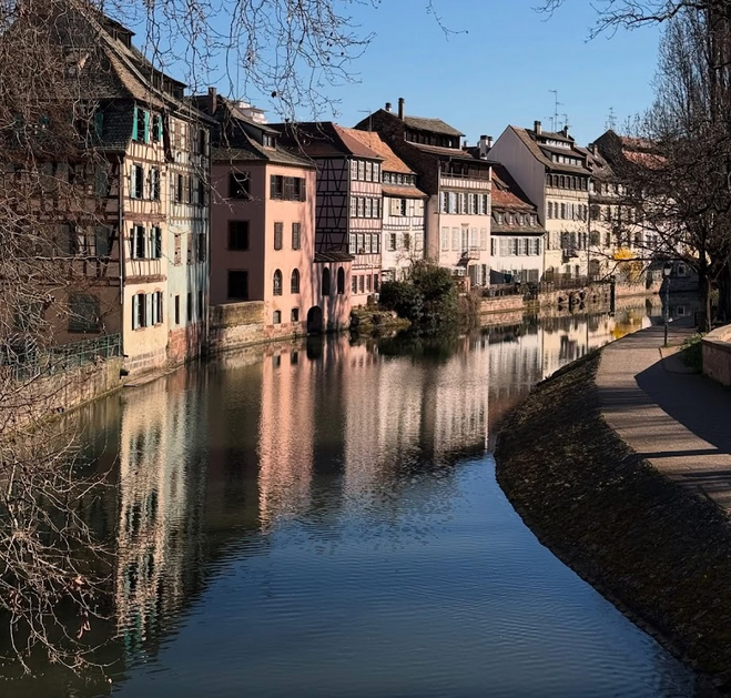 Colorful buildings line a canal with their reflection in the water