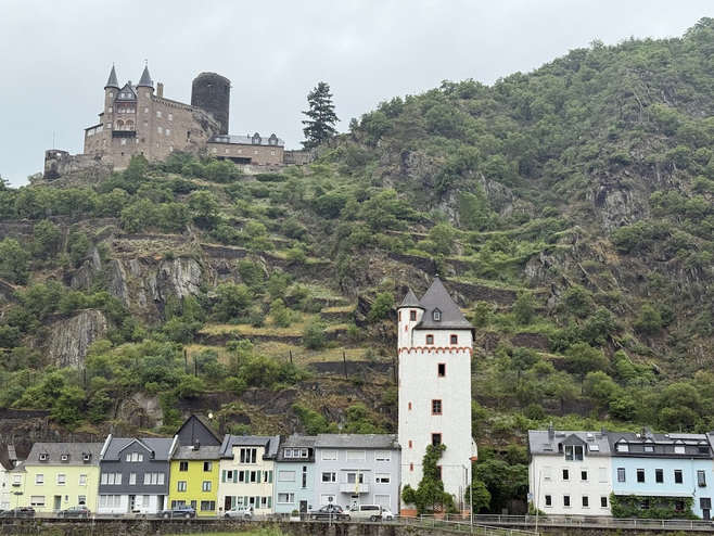 Colorful buildings sit below an old castle on a hill