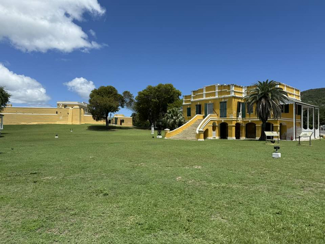 Mustard yello historic fort buildings surrounded by palm trees