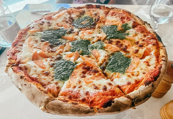 Cheese pizza with dollops of pesto on top