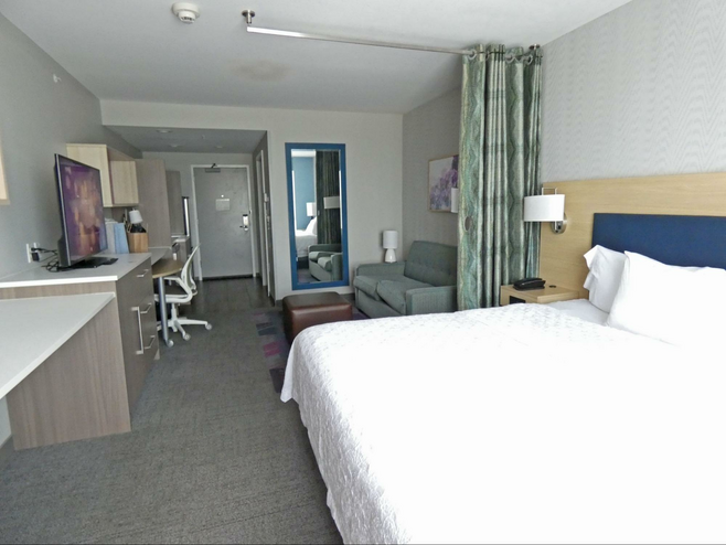 Hotel suite with bed in foreground and living room in back.