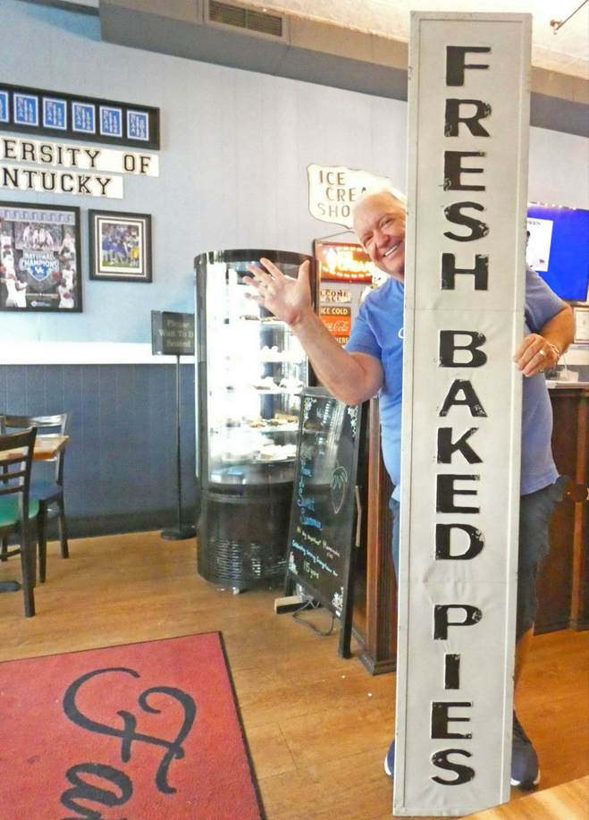 A man behind long sign saying "Fresh baked pies."