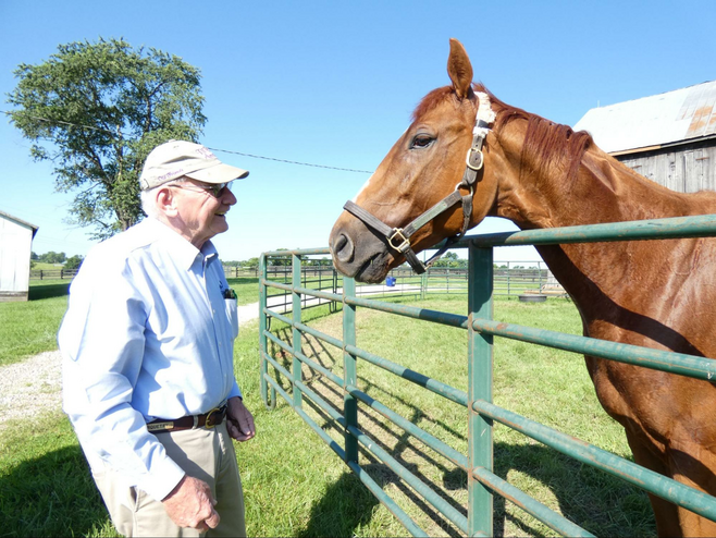 A man in front of fence greeting a horse behind fence.