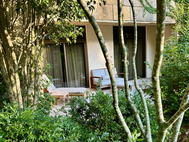Private patio with chaise lounge and loveseat outside a spa level king room at The Umstead hotel.