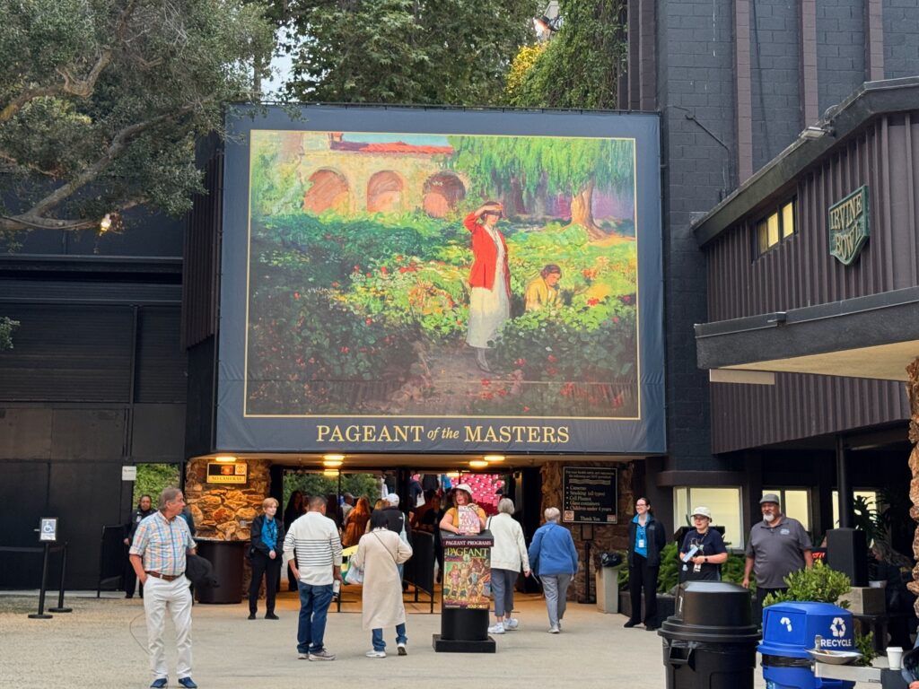 Entry to a venue with a large painting over the entrance and people arriving and departing