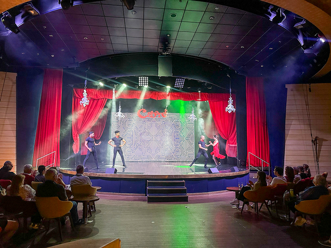 a male dancer with a female dancer dancing on a stage with two male dancers watching
