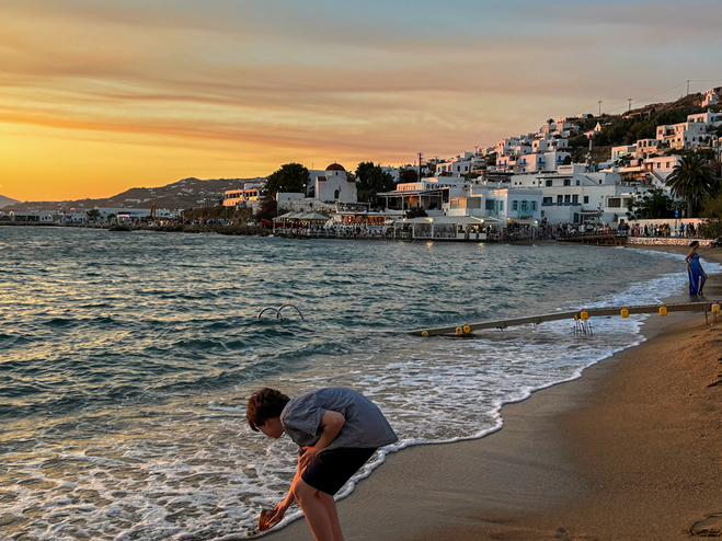 Boy playing on the beach in Santorini during sunset