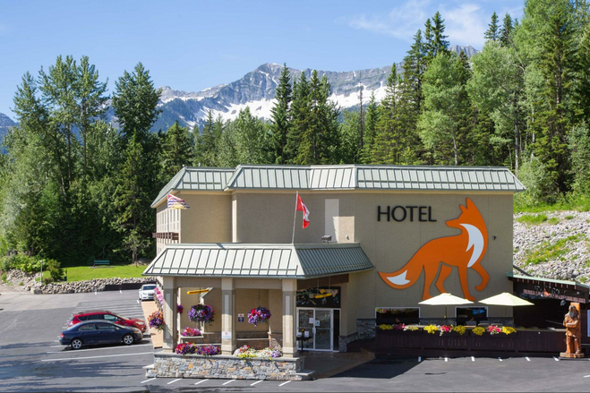 The exterior of the Fernie Fox Hotel with a large picture of its signature orange fox and the Rocky Mountains in the background.