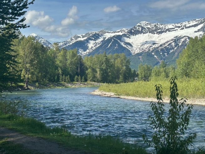 A path runs aside the Elk River with the mountains in the background at James White Park in Fernie, BC.