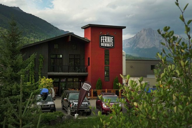 Exterior photo of the Fernie Brewing Co. with the rocky Mountains in the Background.