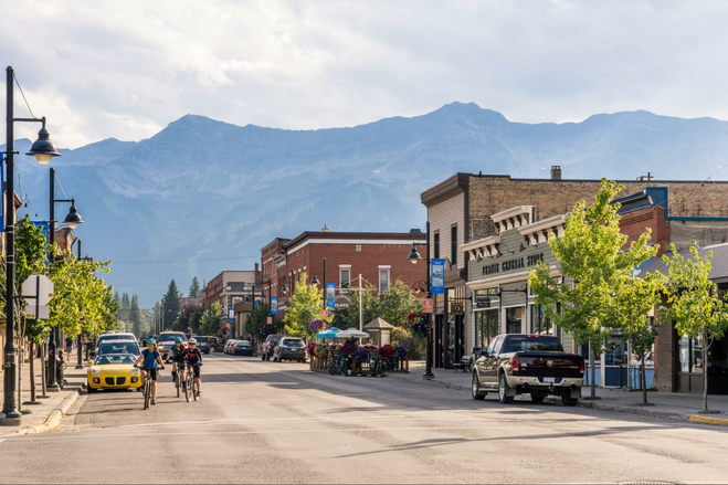Cyclists riding through Fernie's downtown with the Rocky Mountains in the background.