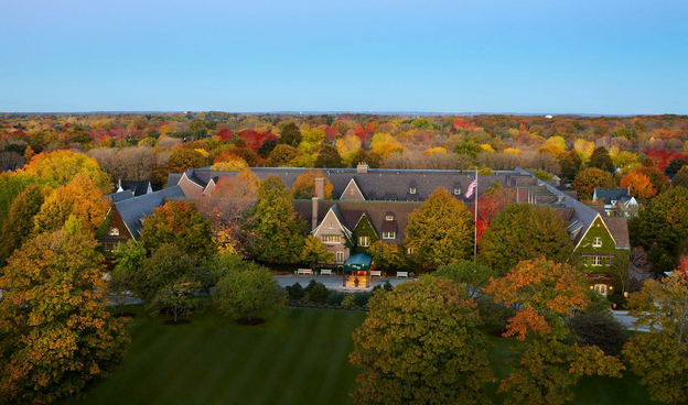 A bird's eye view of the American Club hotel with autumnal trees in the background