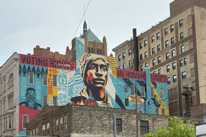Colorful mural of African American man with the words: "Voting Rights are Human Rights" surrounding his head. Around him are words like "liberation movement", "equality", and "we are related" with geometric shapes in the background. 