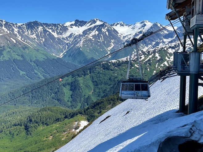 A tram ascends the mountain with Chugach Peaks surrounding 