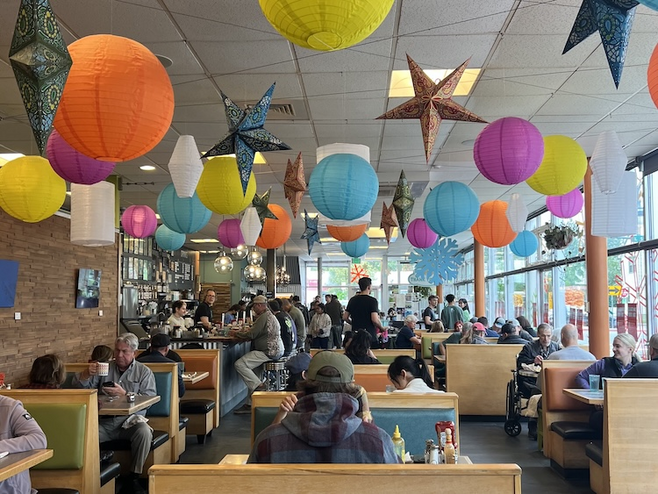 Colorful interior of Snow City Cafe with diners sitting in booths. 