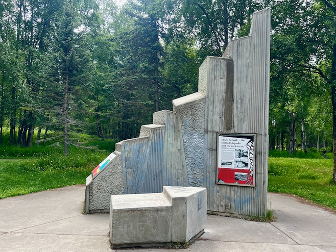 Concrete monument in Anchorage Earthquake Park showing lowered earth levels 