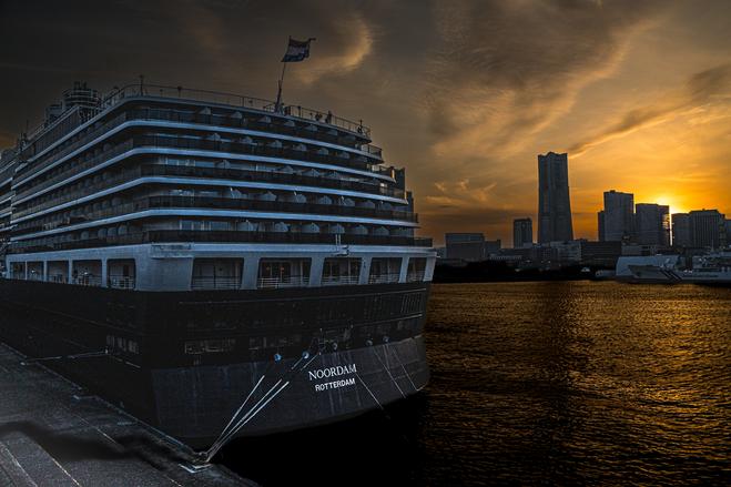 Stern of a ship with silhouette of buildings against a setting sun