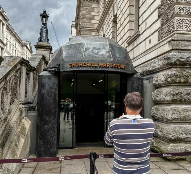 A man taking a photo of the entrance to the secret Churchill War Rooms, one of the best things to do near Buckingham Palace.