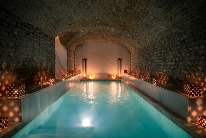 long pool surrounded by candles and lamps