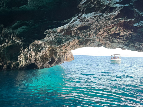 A small boat sailing into a pretty sea cave.