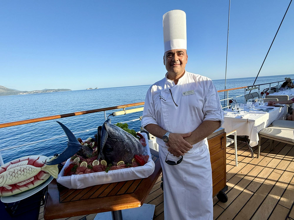 Chef standing next to freshly caught tuna on ship deck.