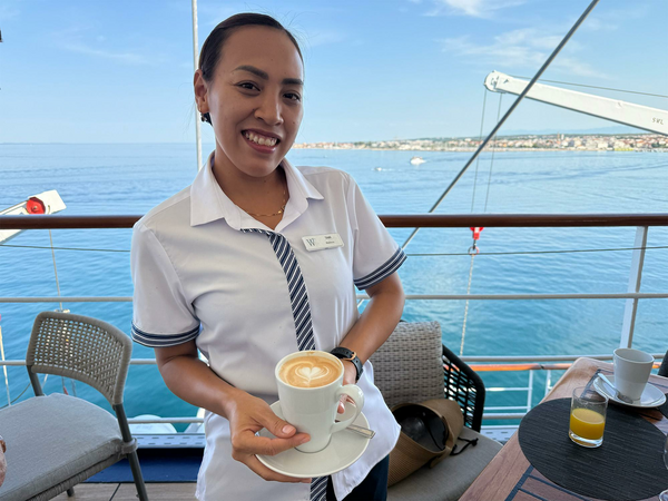 Cruise staff member serving coffee with heart shape in coffee foam.
