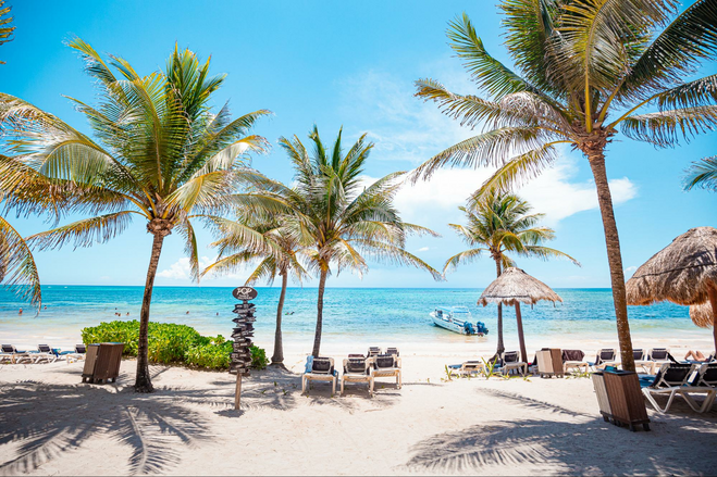 Beach with sand, palm trees and umbrellas at Riviera Maya, Mexico family all-inclusive resort