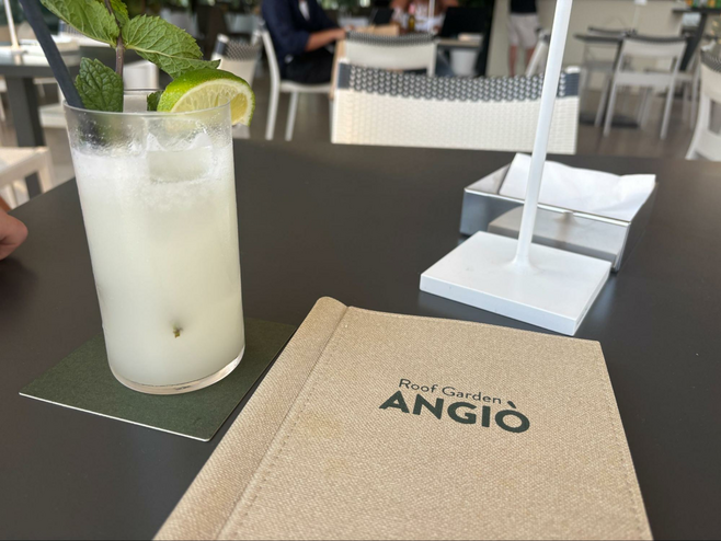 Pina colada cocktail at Roof Garden Angio and menu on table