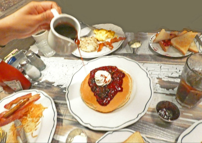 Food dishes on table with Boysenberry Pancakes in center.