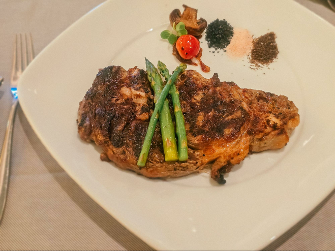 Ribeye steak and asparagus on a plate on board Discovery Princess in Alaska.