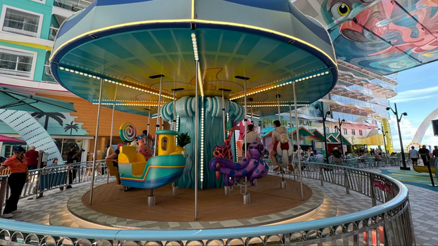 Vibrant carousel in the middle of a deck with a purple creature, boat, lollipop and other horses.
