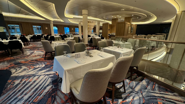 dining room interior with several upholstered chairs next to tables with small plates and glassware. 