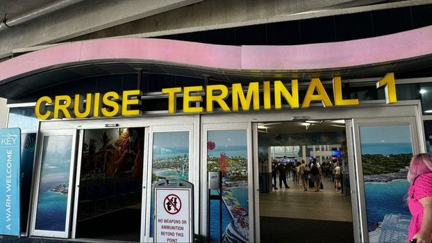 yellow sign that says cruise terminal 1 above sliding doors with images of Royal Caribbean boats. 