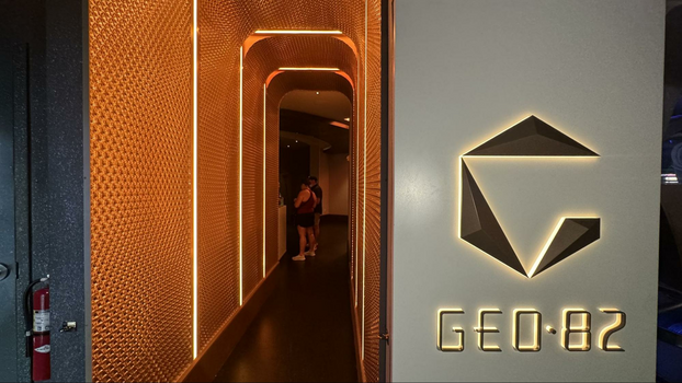 Yellow illuminated corridor next to silver GEO-82 sign at the entrance to the bar.
