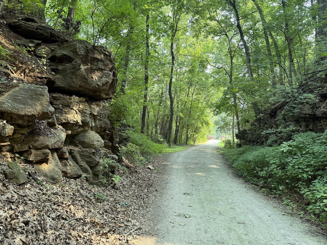 The MKT recreational trail in Columbia, Missouri, is largely shaded with many rock outcrops and trees.