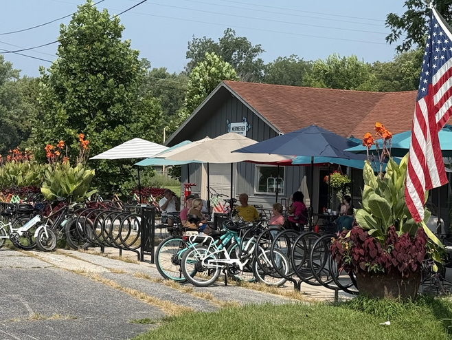 The Meriweather Cafe is an outdoor brunch and lunch spot with bicycles and shaded tables and an American flag flying in Rocheport, Missouri.