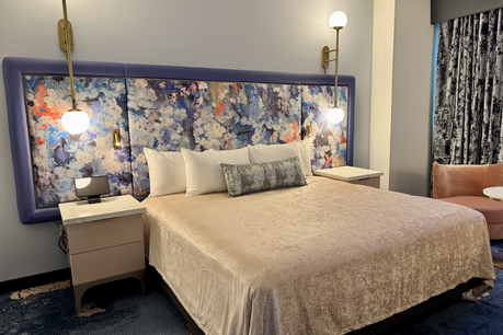 Hotel room at Universal Helios Grand Hotel with floral headboard, velvety bedspread and gold accents.