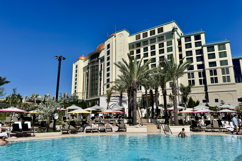 Universal Helios Grand Hotel pool with palm trees and hotel in the background.