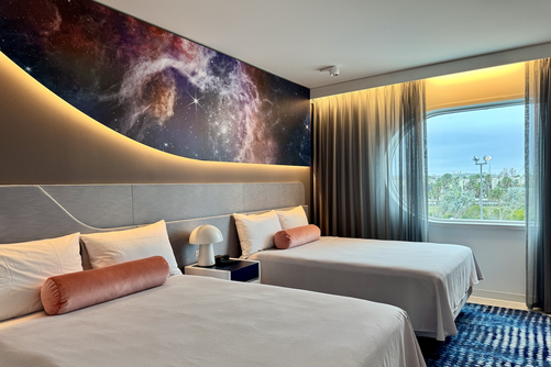 Hotel guest room with outer space mural above two queen beds at Universal Stella Nova Resort.