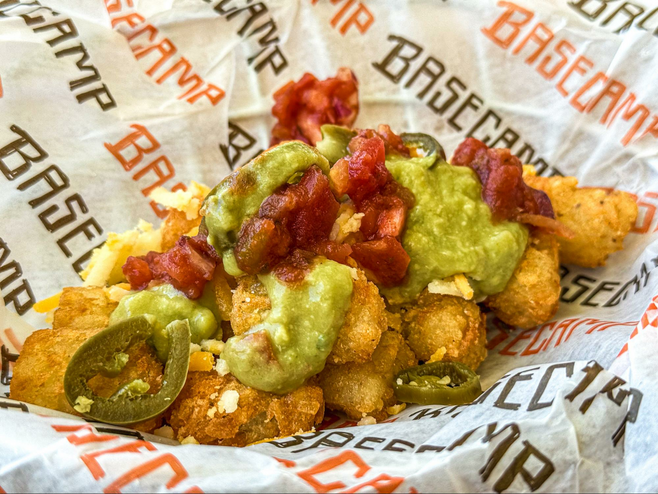 Tater tots topped with guacamole and salsa